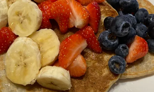 The pancakes covered with banana, blueberries and strawberries