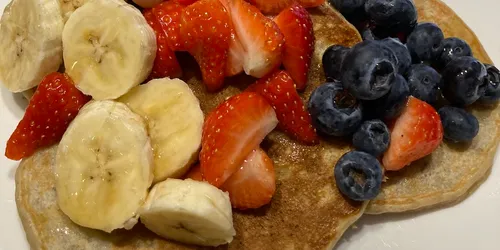 The pancakes covered with banana, blueberries and strawberries